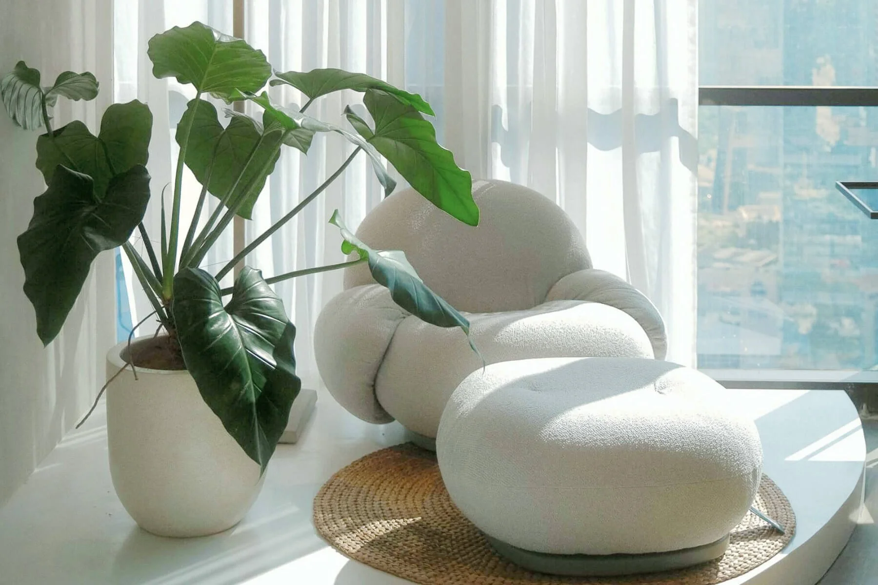 Organically shaped armchair with pouf in a calm biophilic interior setting with abundant sunlight.