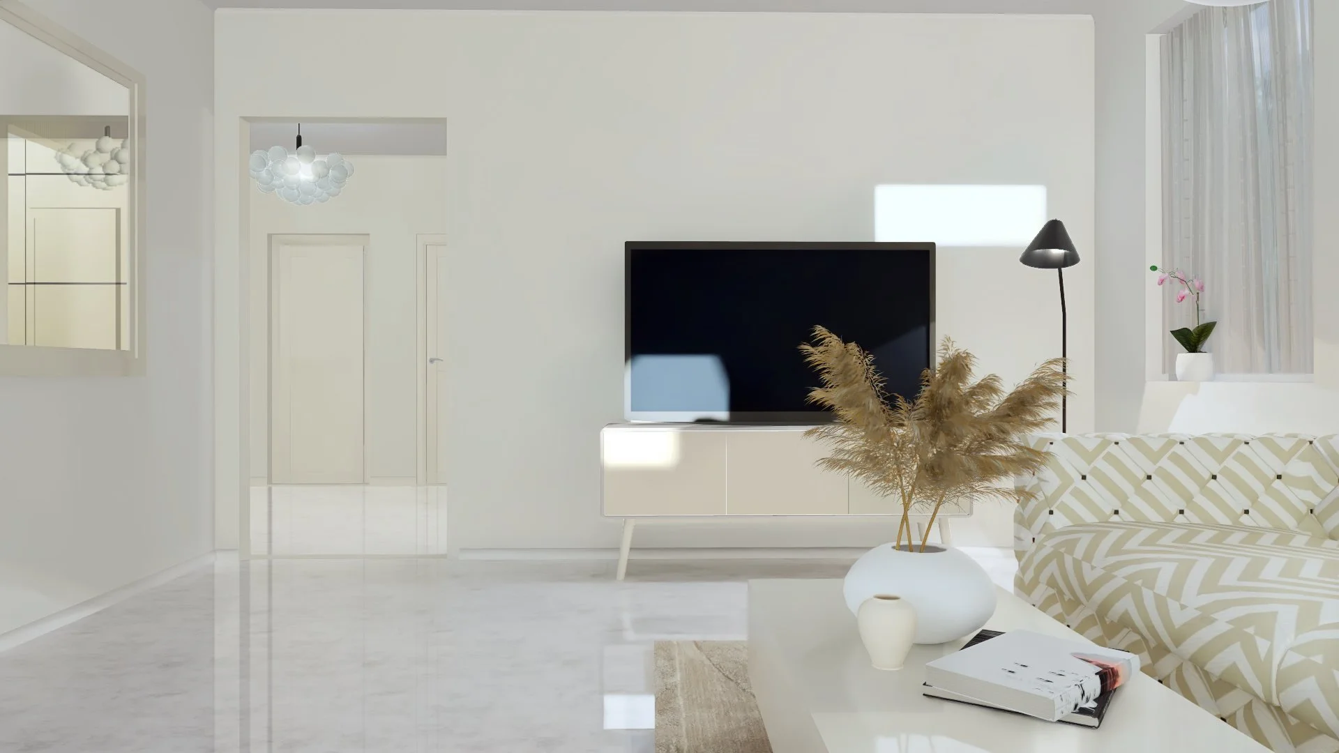 Bright living room with white walls, a modern TV on a white stand, a beige patterned sofa, a black floor lamp, and a white coffee table holding a vase with dried pampas grass, a small white vase, and a magazine. A window with sheer curtains and a pink orchid in a white pot are visible.