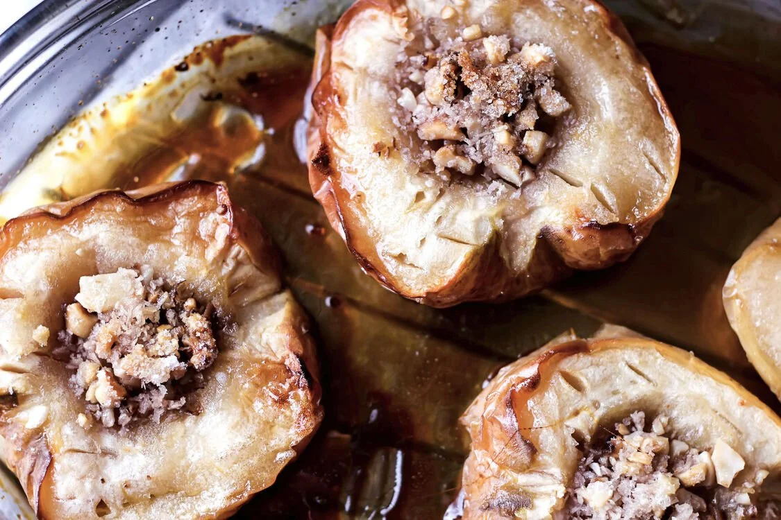 Close up of sliced autumn apples roasting with organic walnuts, cinnamon and cloves in a clean oven.