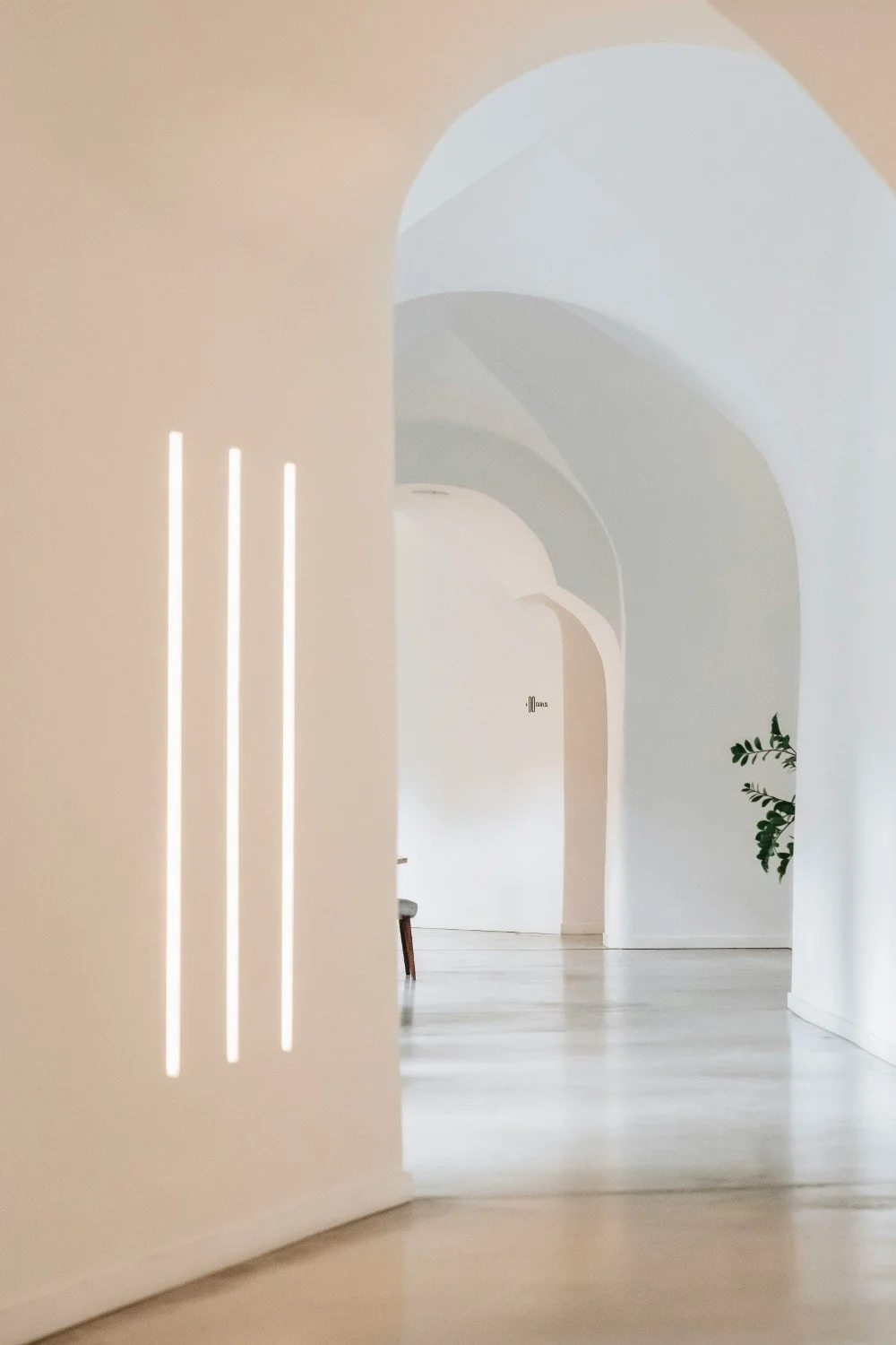 Example of light strategy of three narrow wall lights that visually warm up cold white organic interior.