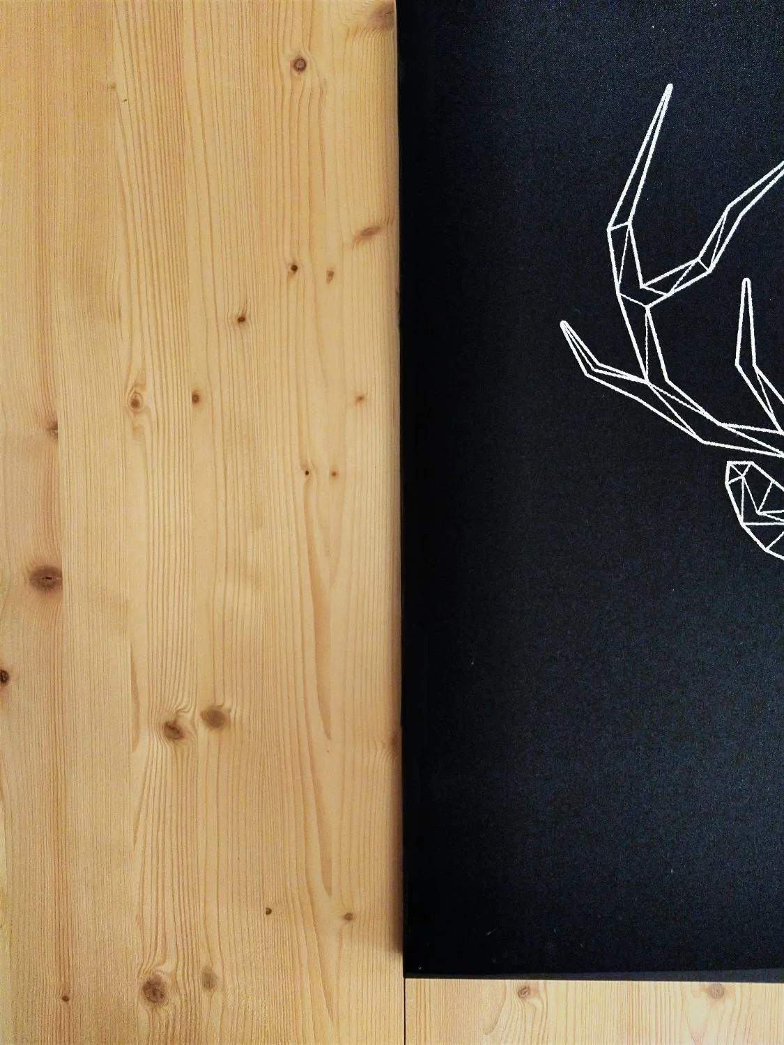 Half of black painting hanging on spruce cladded wall