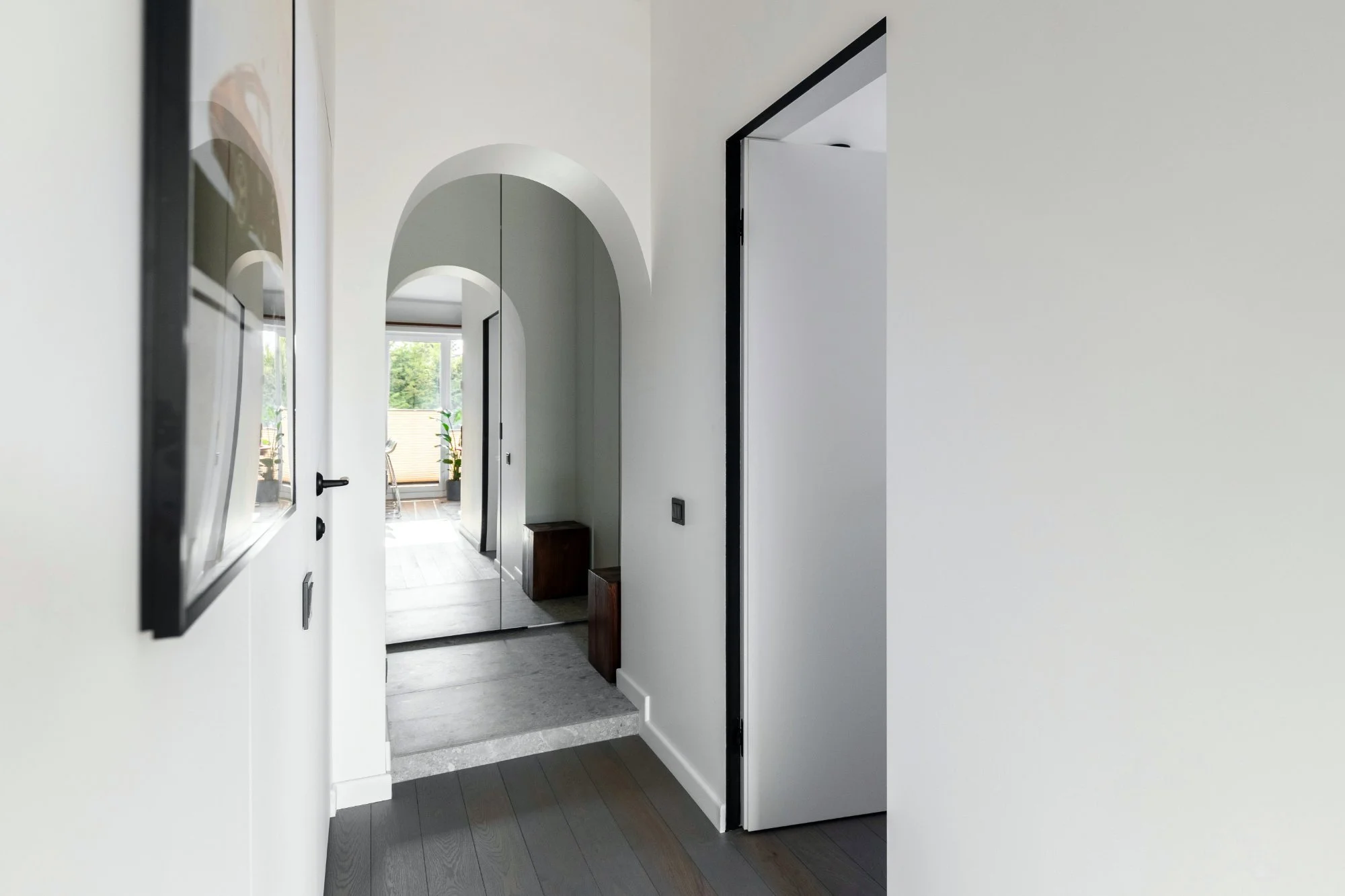 Minimalist white modern hallway architecture showing a structured corridor transition with arched floor mirror