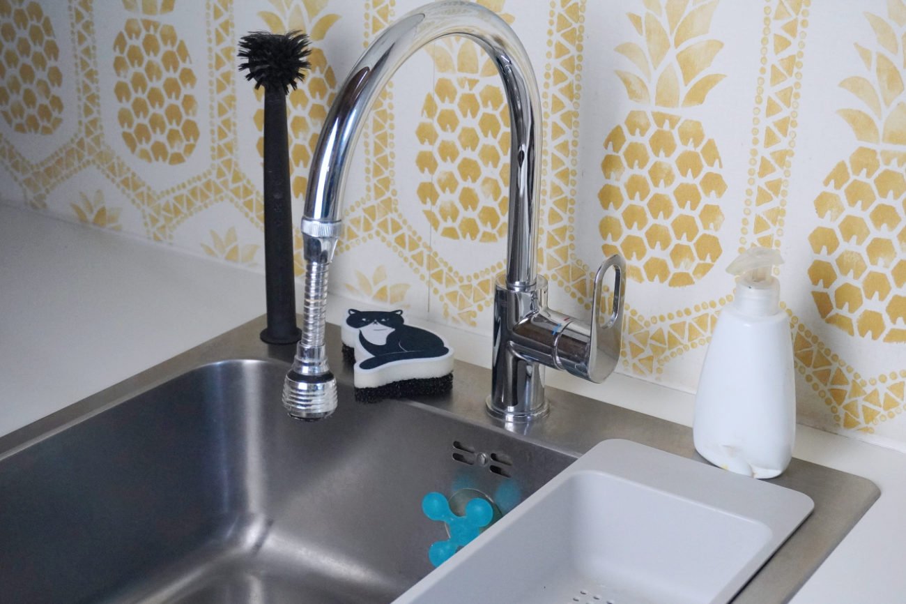 A large stainless steel sink with a chrome tap, sponge, and draining area, highlighting practical utility room essentials for heavy-duty household tasks.