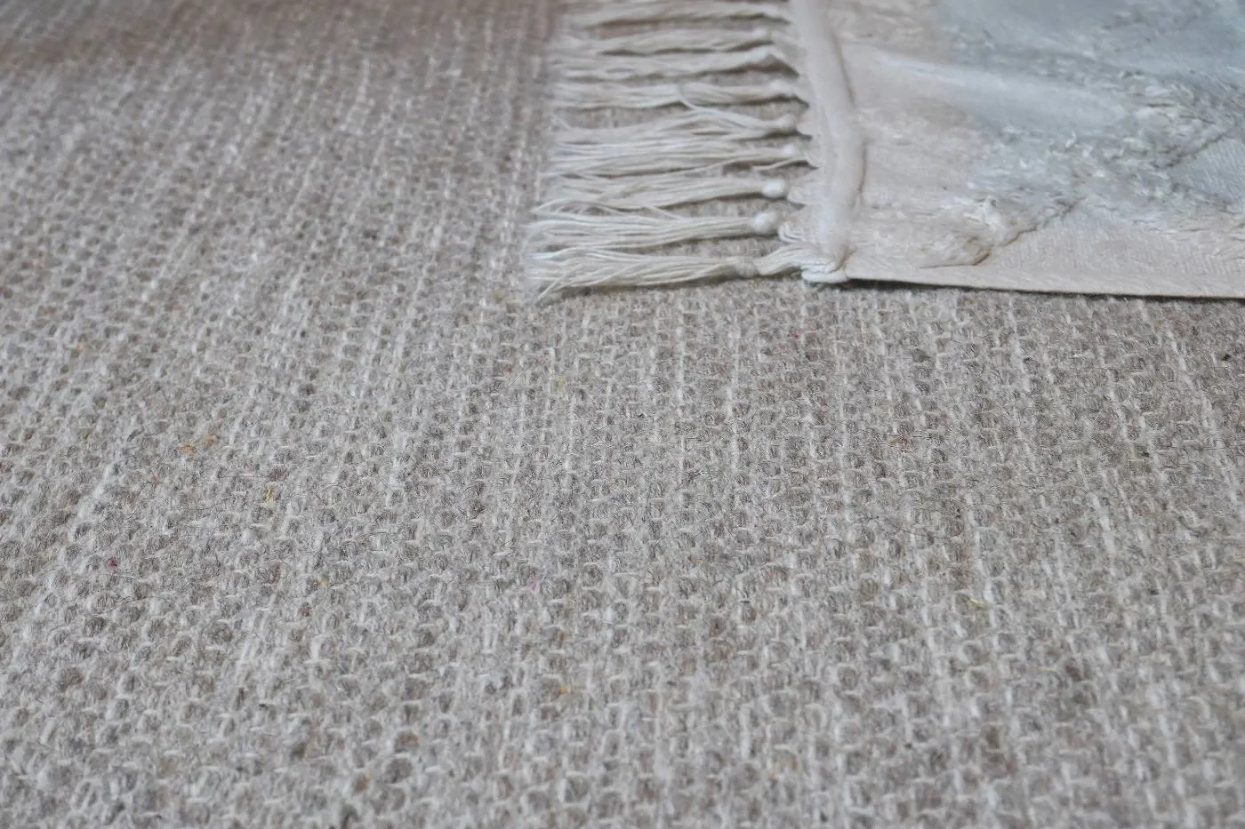 Handwoven beige cotton–wool rug texture close-up