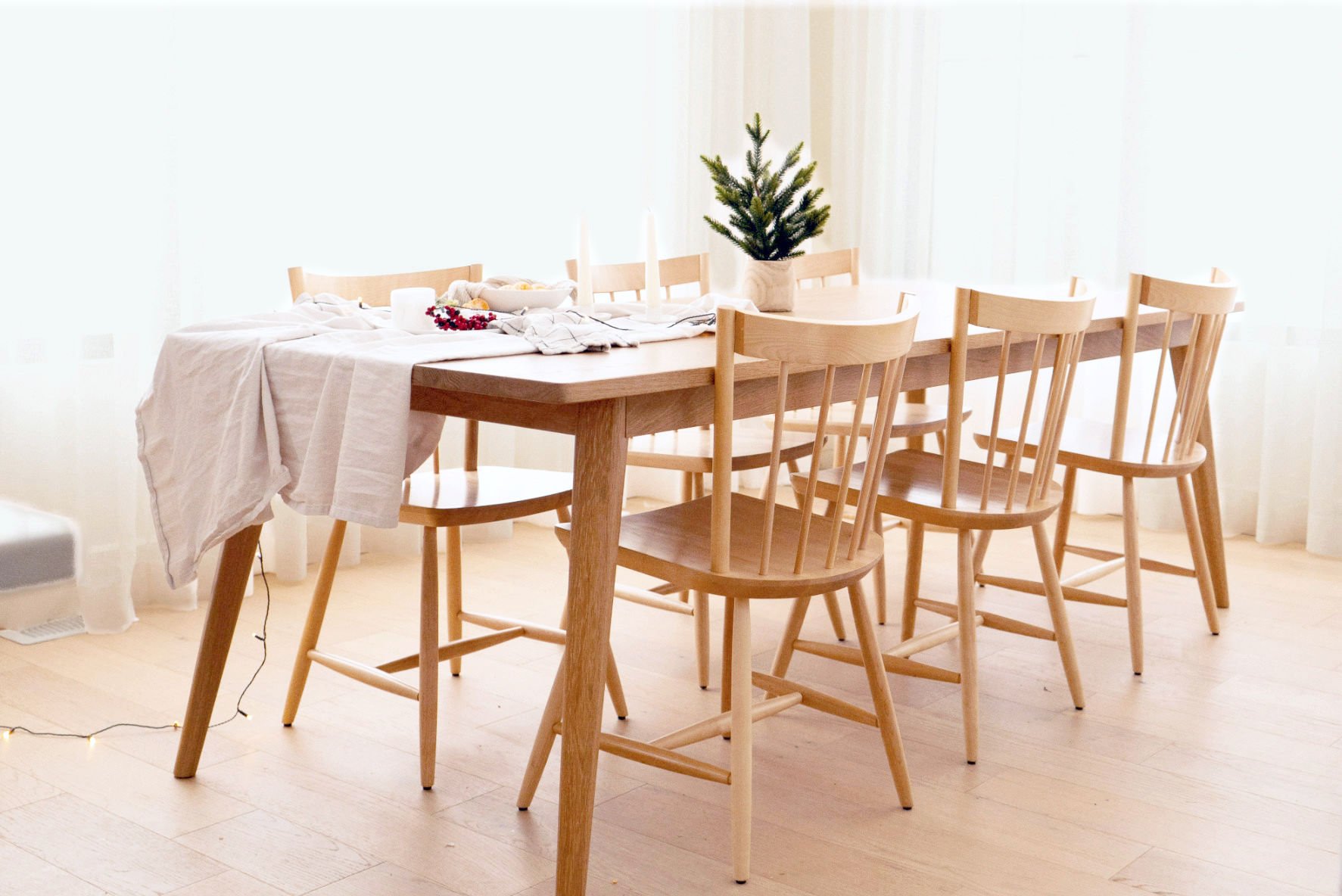 Light oak Scandinavian dining table with clean lines, set in a bright minimalist interior
