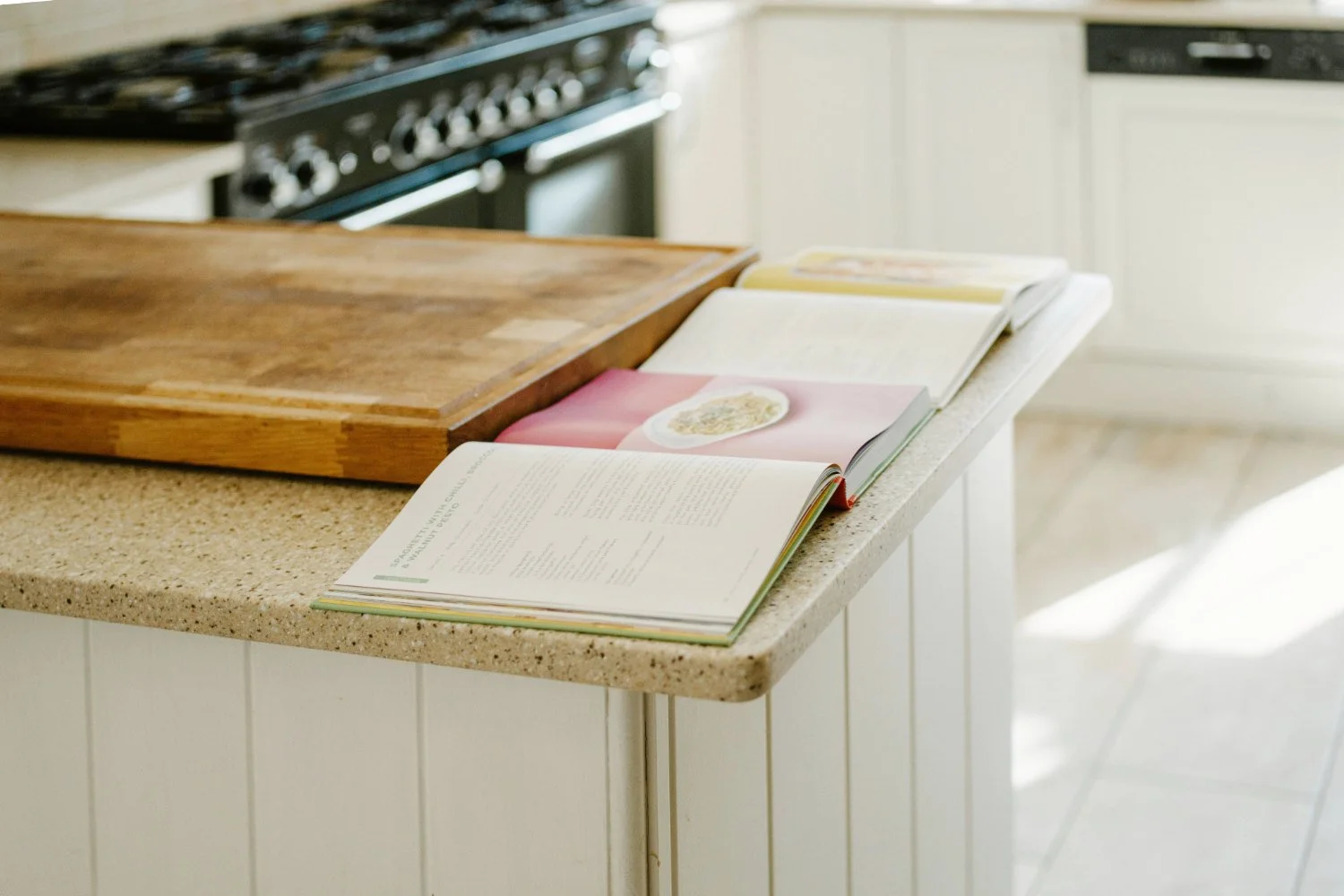 Open cookbook on a kitchen counter illuminated by bright midday sun, highlighting functional kitchen layout tips.