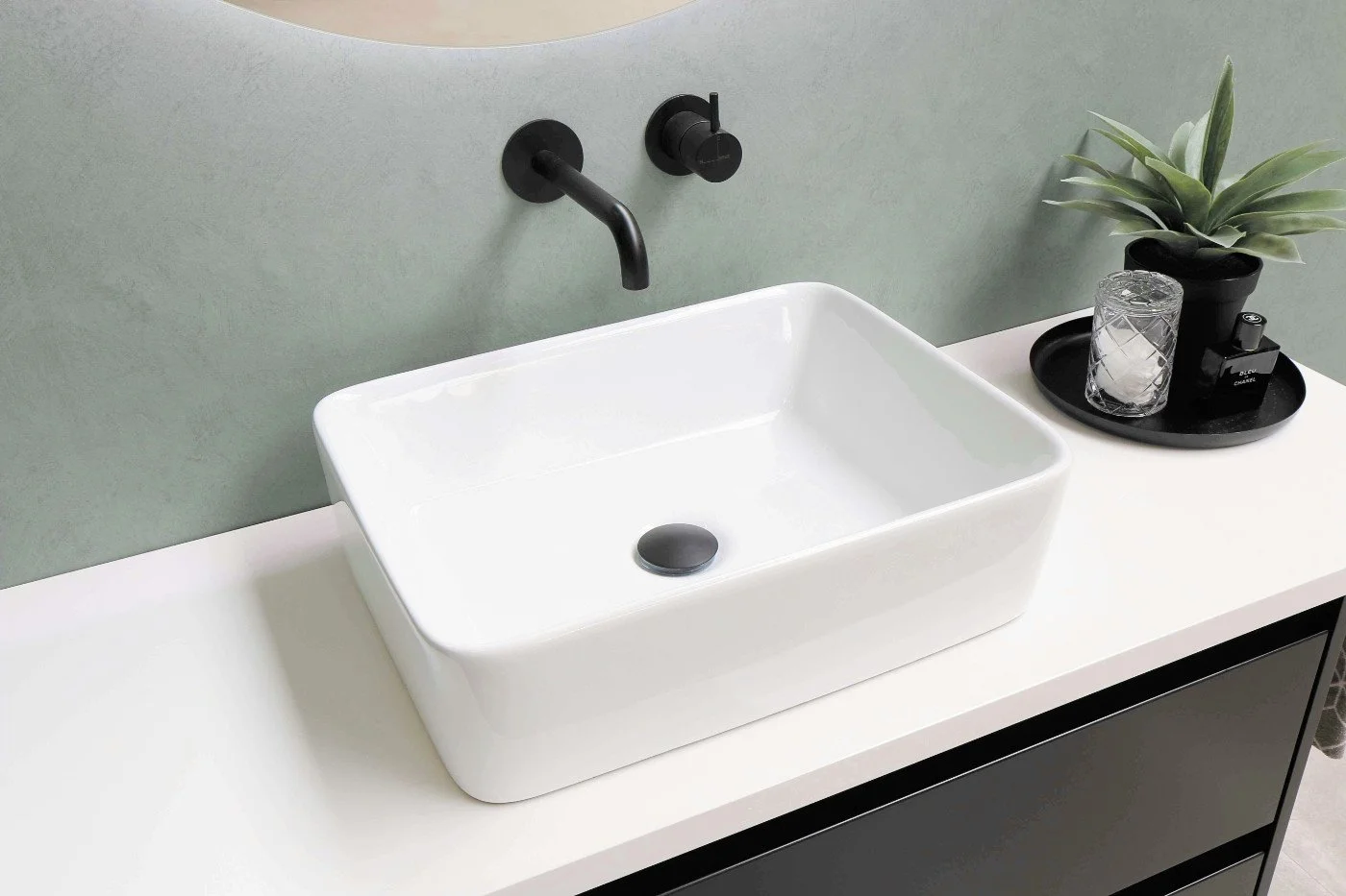 Bathroom interior with a sink and green microcement walls showcasing a seamless mineral finish.