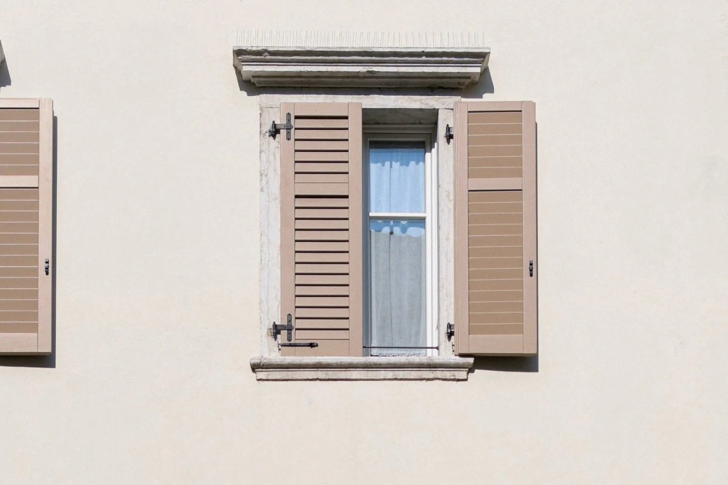 Close-up of open wooden window shutters on a stone building, illustrating flexible external shading.