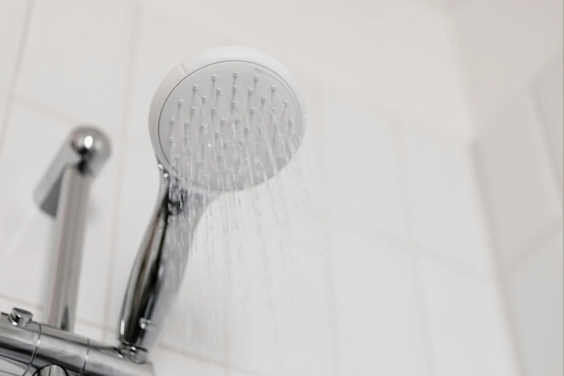 Shower with running water creating steam, highlighting areas where moisture can accumulate and encourage mould growth if not wiped or ventilated