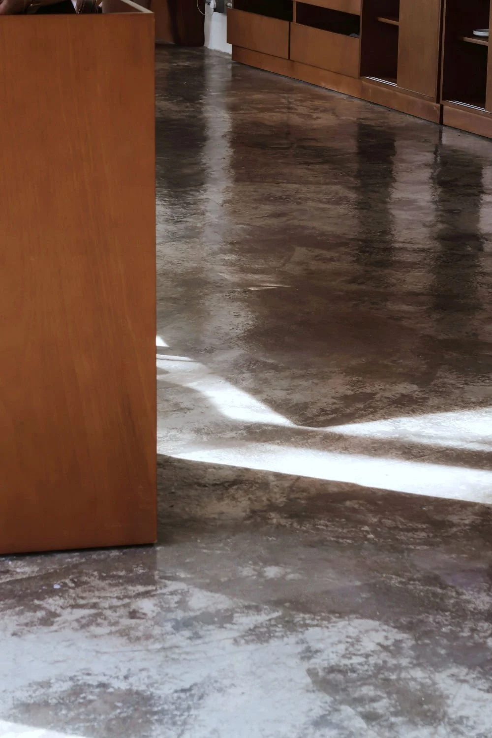 Minimalist interior with a polished concrete floor and stone wall, demonstrating high thermal lag materials.