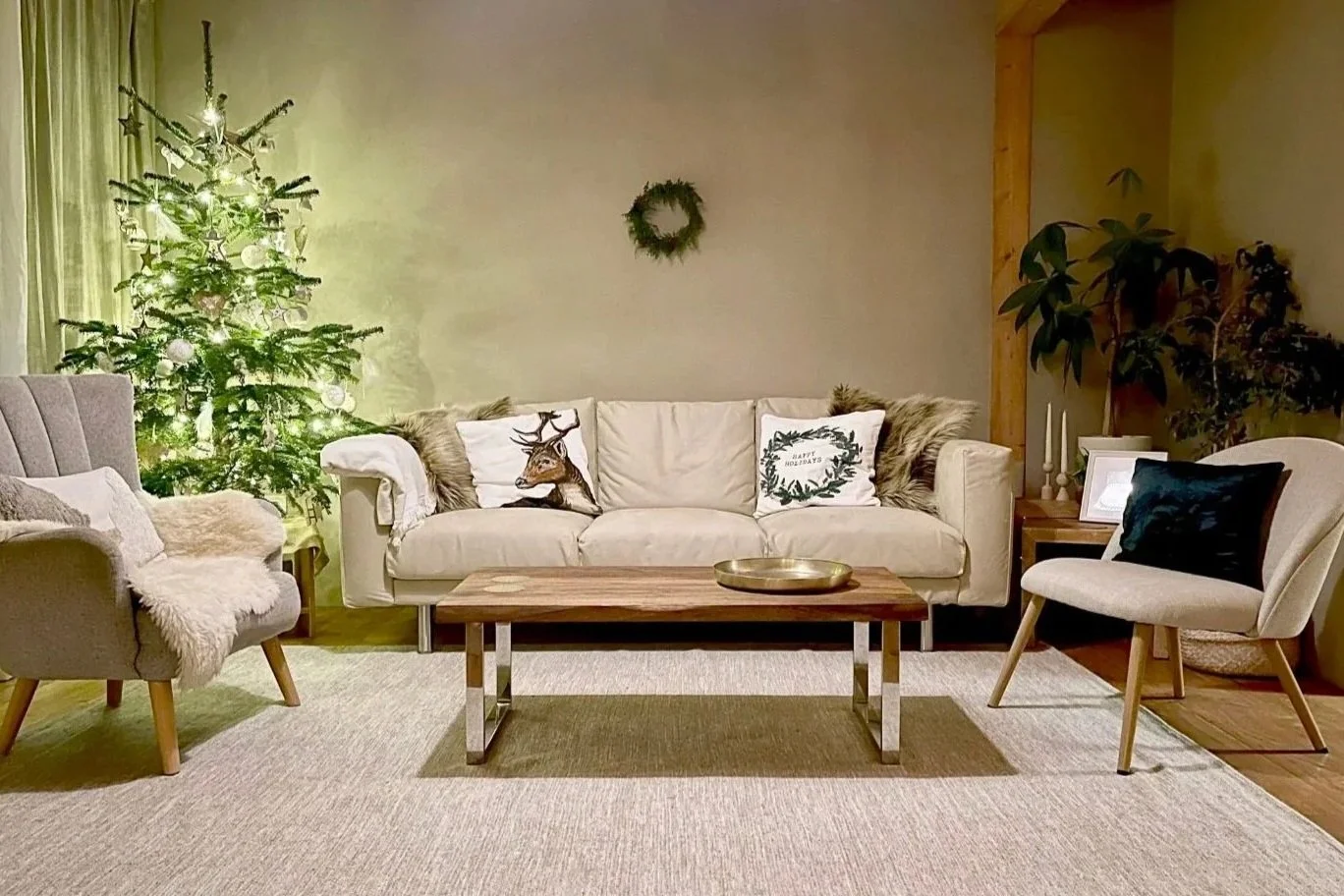 Upgraded sustainable living room with beige sofa, cotton–wool rug, solid wood coffee table, two neutral chairs, and Christmas tree