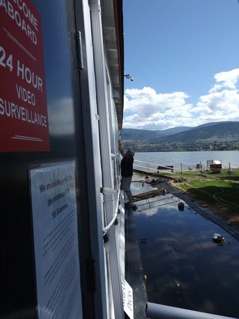 Penticton-Flood-Matt-removing-a-pane-of-glass-from-the-window-so-that-an-electric-cable-can-be-passed-through-Matt-on-the-edge-e1503089998997.jpg