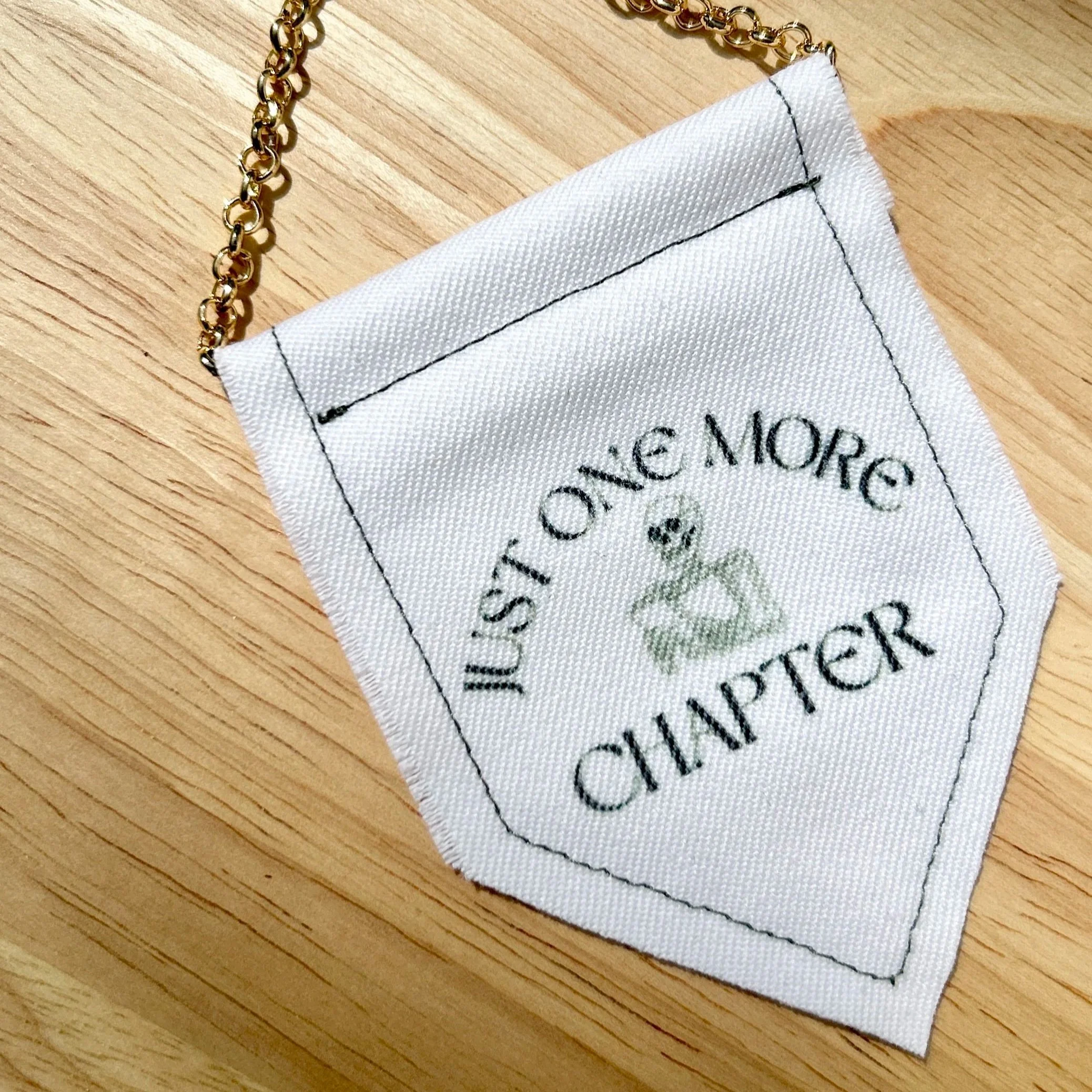 Handmade upcycled white fabric mini banner with "just one more chapter" and an image of a skeleton reading a book - design infused ink design