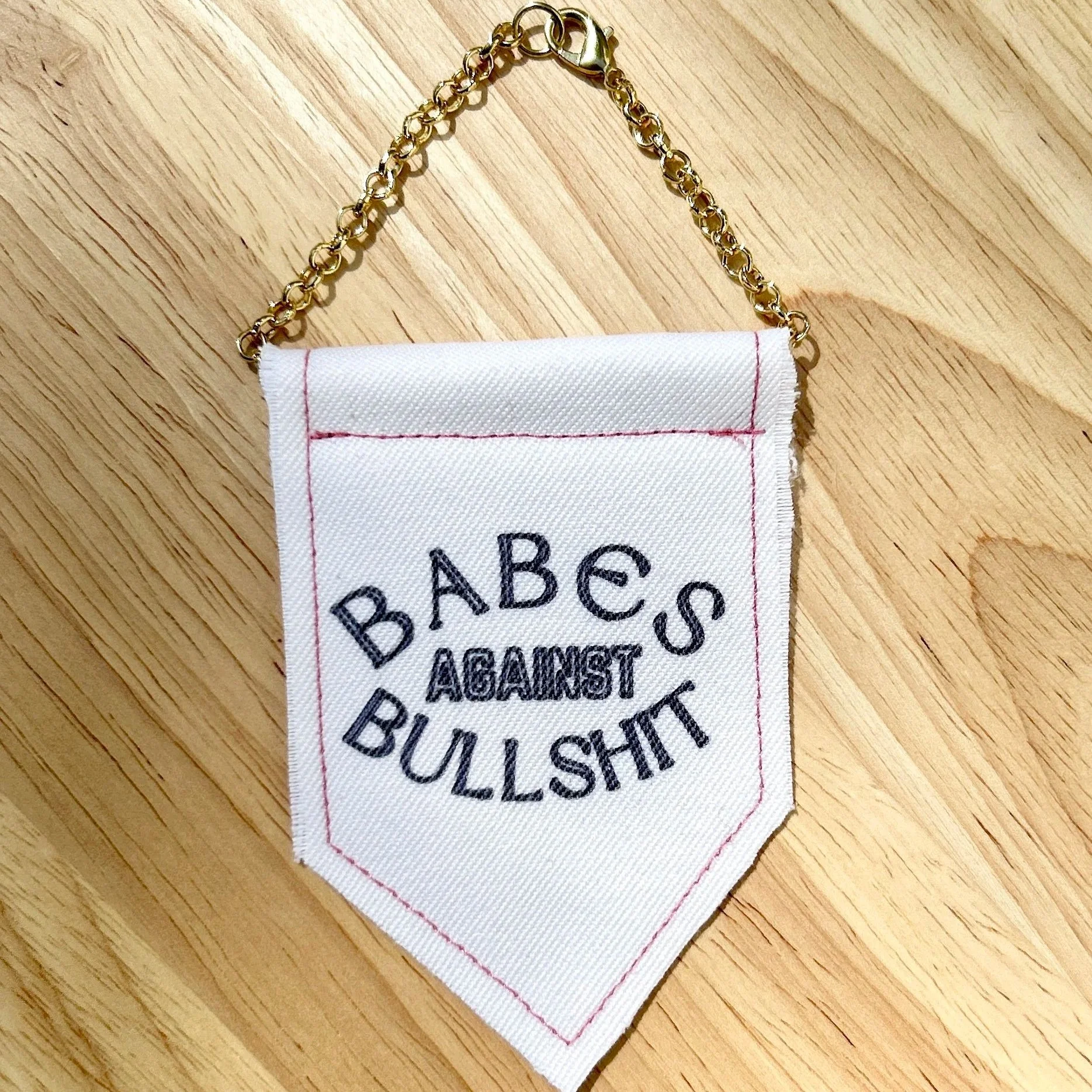Handmade upcycled white fabric mini banner with "babes against bullshit" in block letters - design is in black infused ink