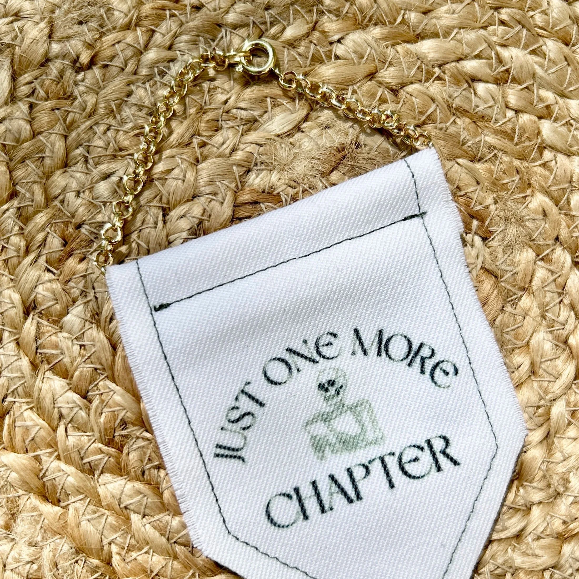 Handmade upcycled white fabric mini banner with "just one more chapter" and an image of a skeleton reading a book - design infused ink design