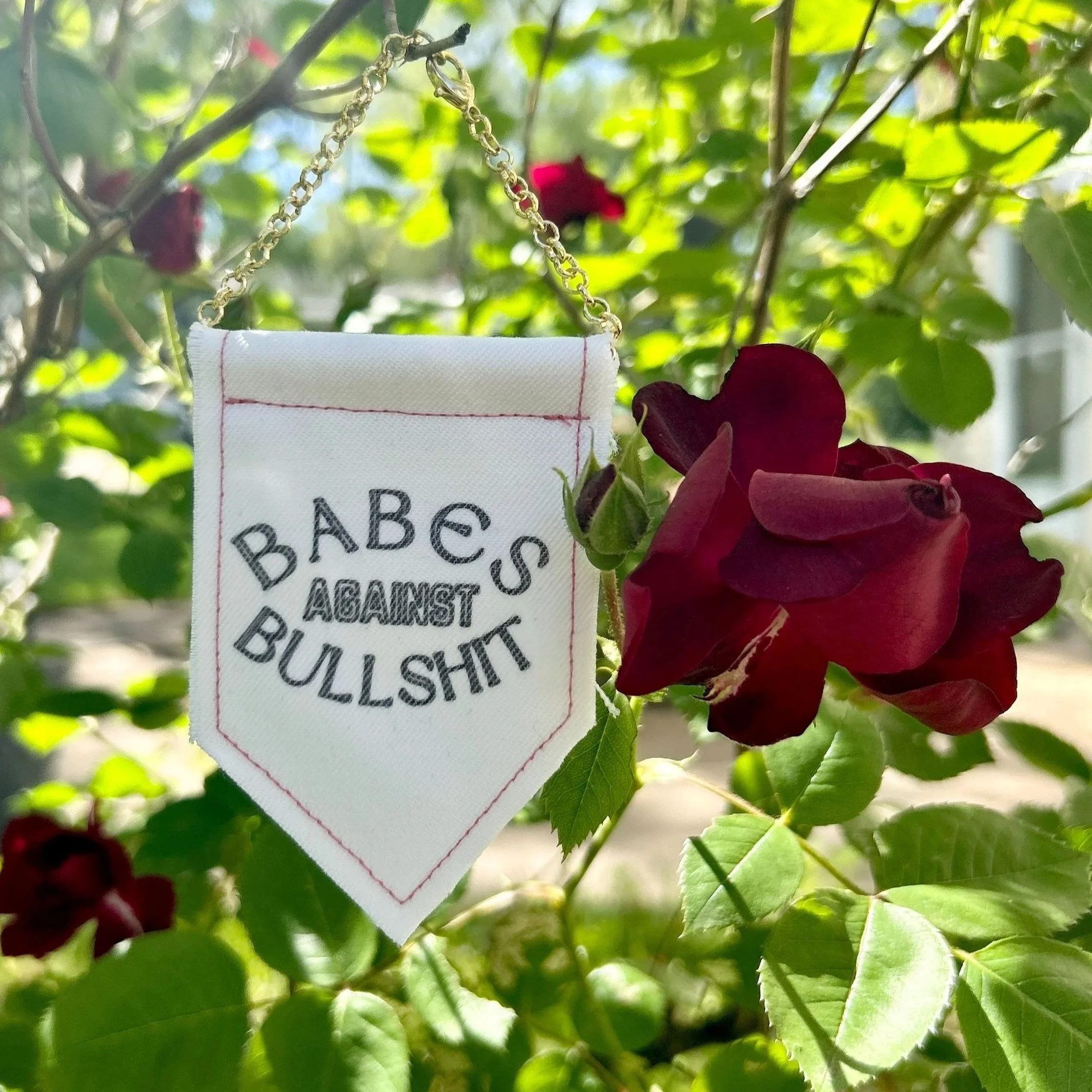 Handmade upcycled white fabric mini banner with "babes against bullshit" in block letters - design is in black infused ink
