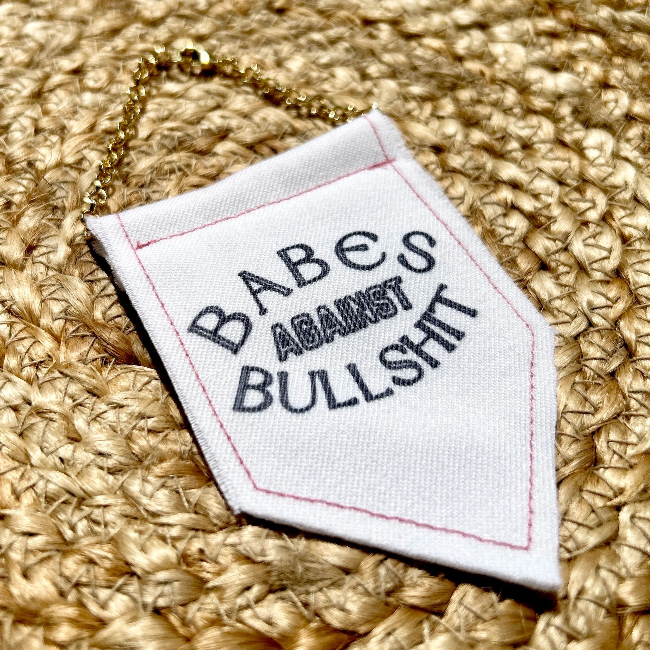 Handmade upcycled white fabric mini banner with "babes against bullshit" in block letters - design is in black infused ink