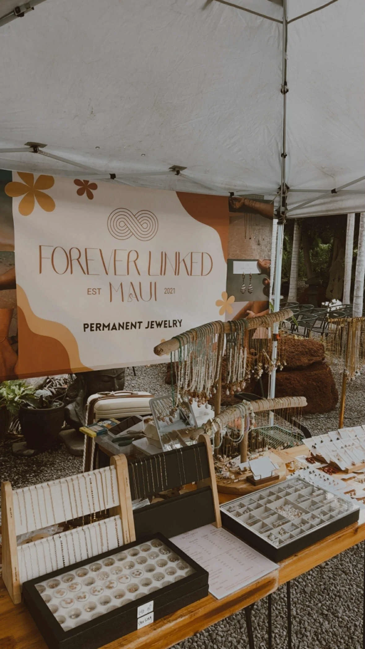 The forever linked maui booth with chains, charms, and premade necklaces, bracelets, and earrings displayed on the table.