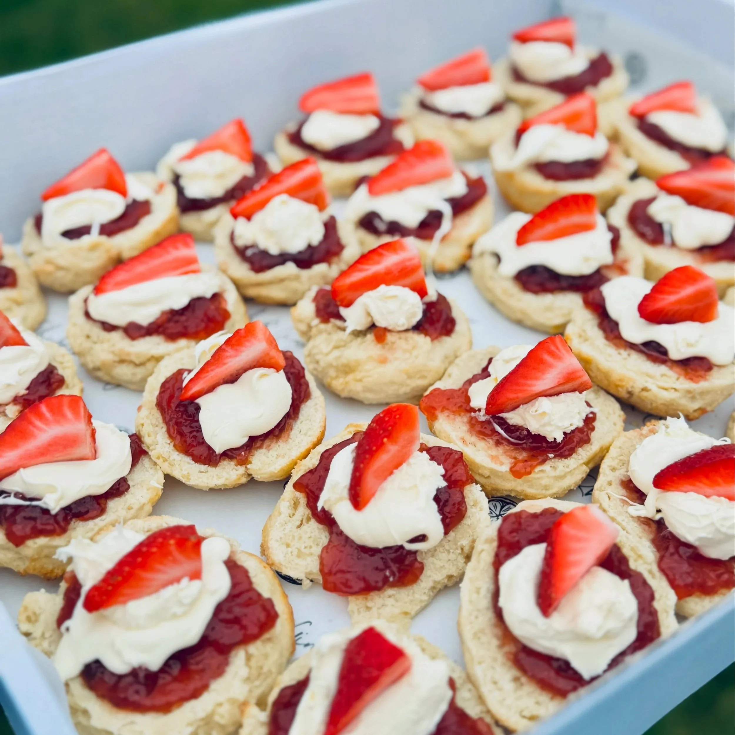 Assorted strawberry shortcake biscuits with whip and strawberry slices on a white tray.