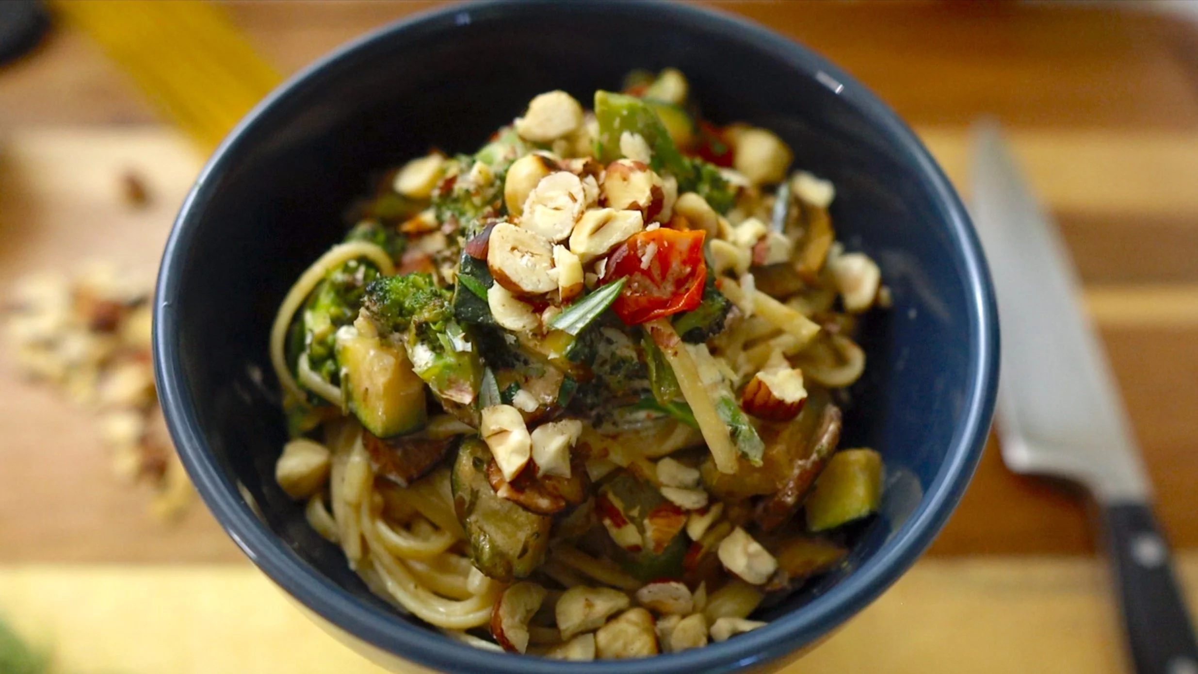 finished pasta dish with cooked noodles, veggies and chopped hazelnuts