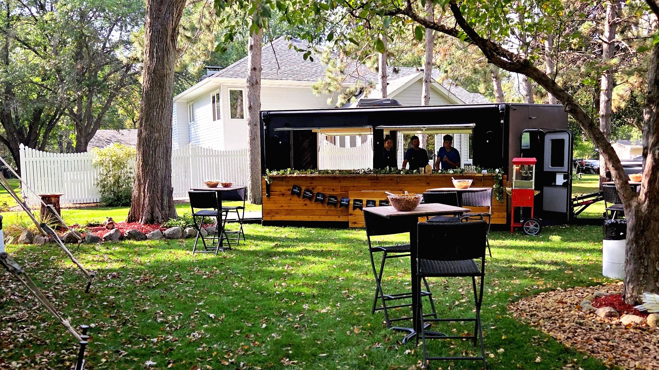 Minnesocial North Star mobile bar trailer set up in a landscaped Minnesota backyard, styled and ready for an outdoor wedding reception with cocktail tables and elegant décor.