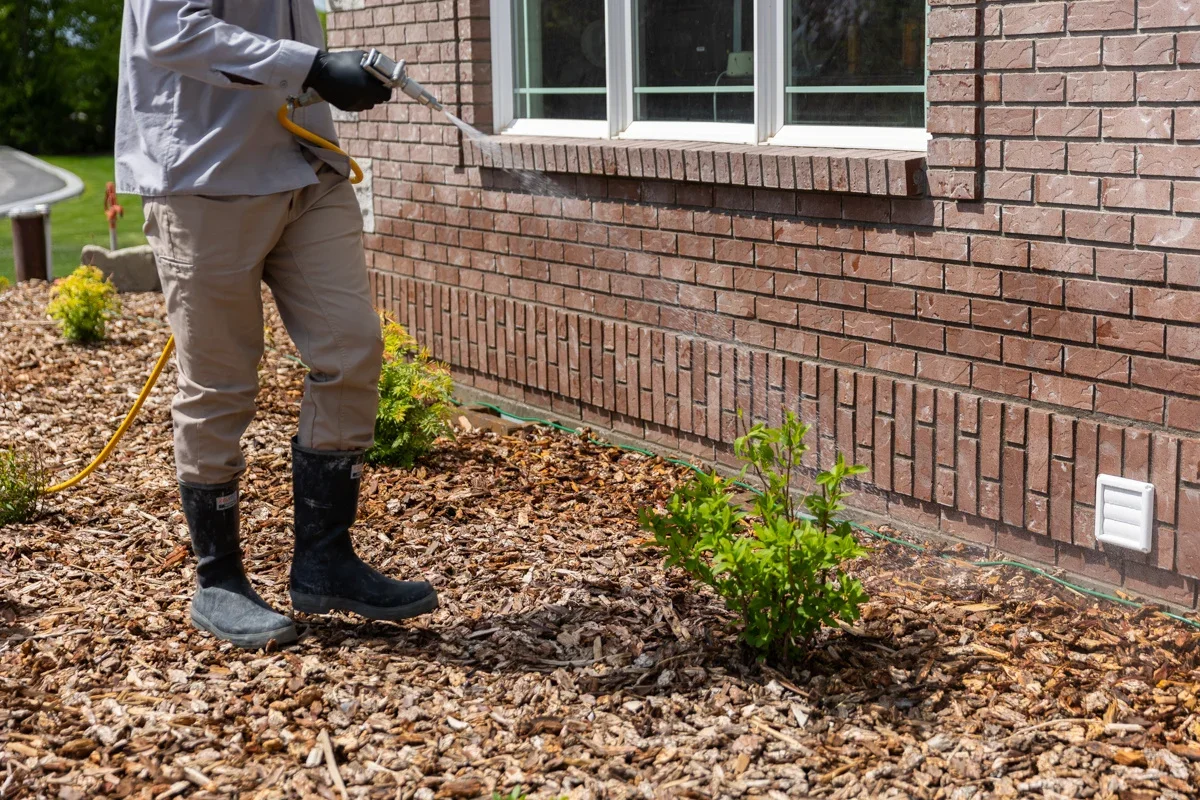 Pest control technician applying exterior perimeter treatment