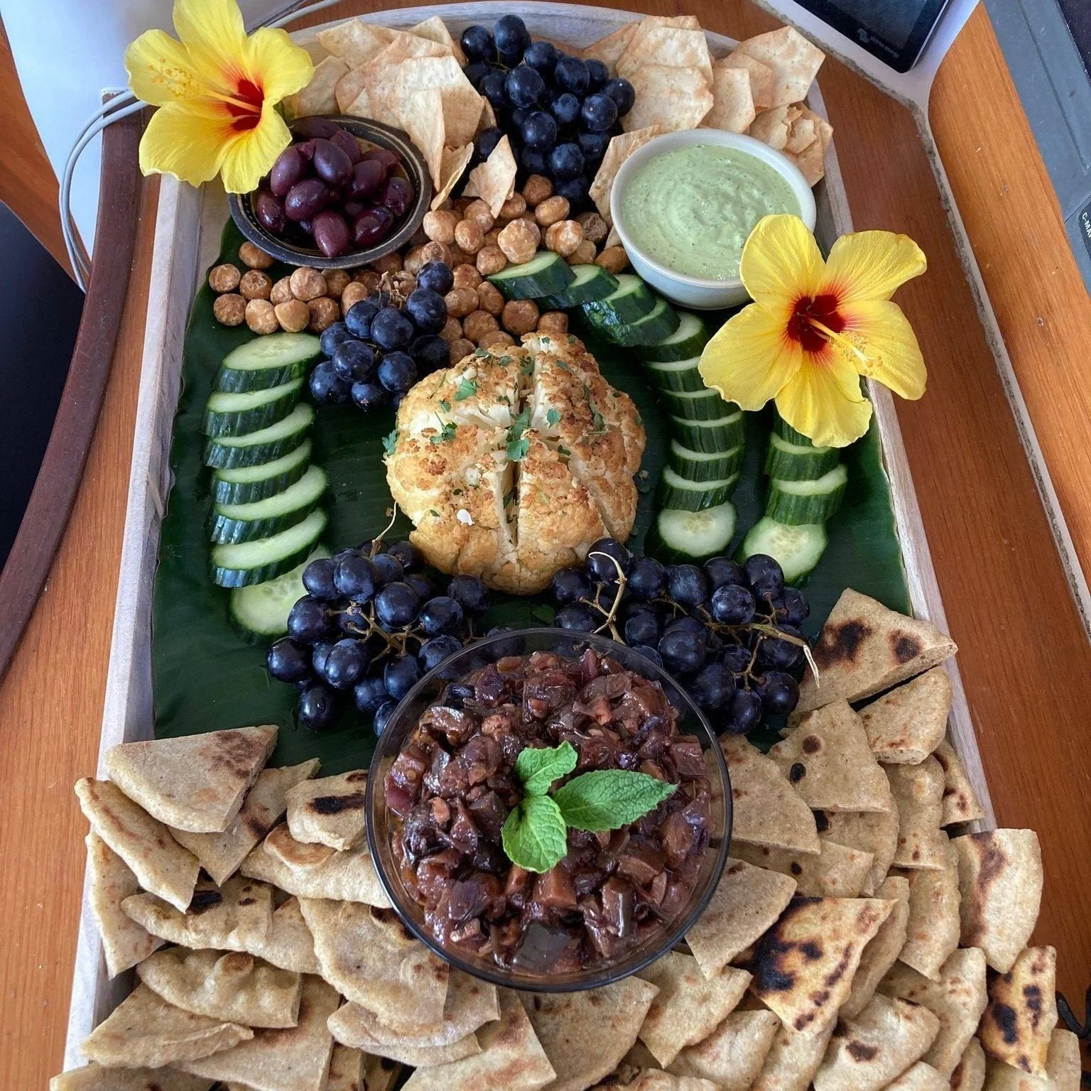 Vegetable Mezze board with roasted cauliflower, green tahini, olives, eggplant caponata, za'atar flatbread and hibiscus flower on afternoon sail, swim and snorkel cruise