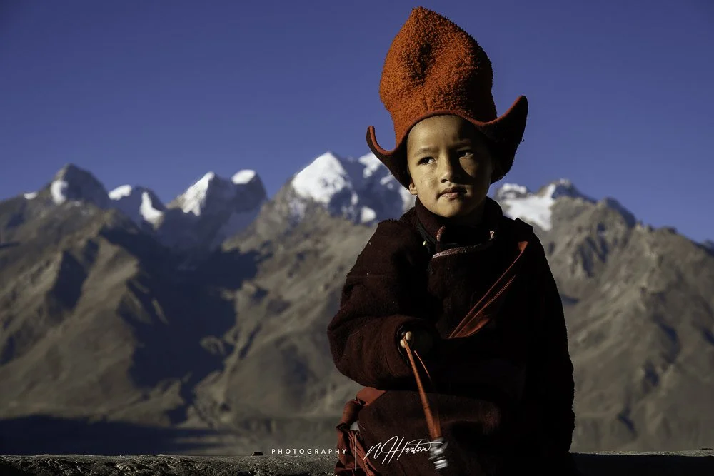 Young monk against snow peaked mountains in Zanskar valley