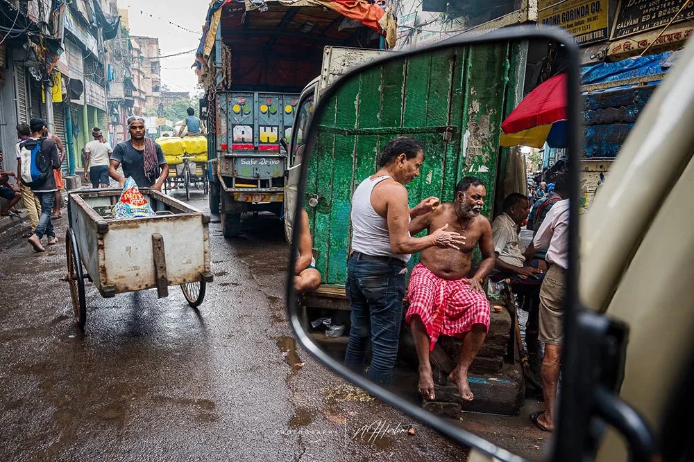 Busy street scene reflected in car mirror, Kolkata, India
