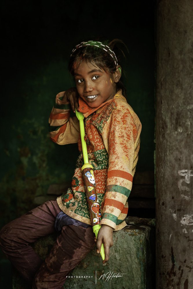 Girl-in-doorway with-water-pistol-at-Holi-festival-India