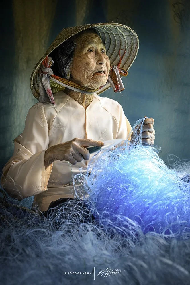 Portrait of old lady mending fishing net, Hoi An, Vietnam.