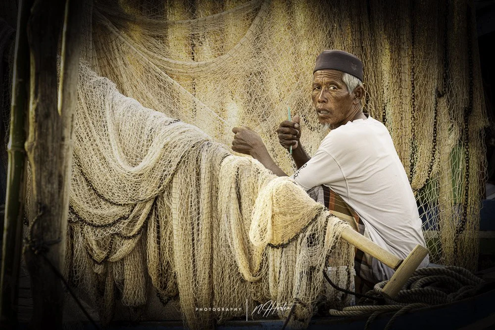 Mending fishing nets on small boat Phnom Penh, Cambodia.
