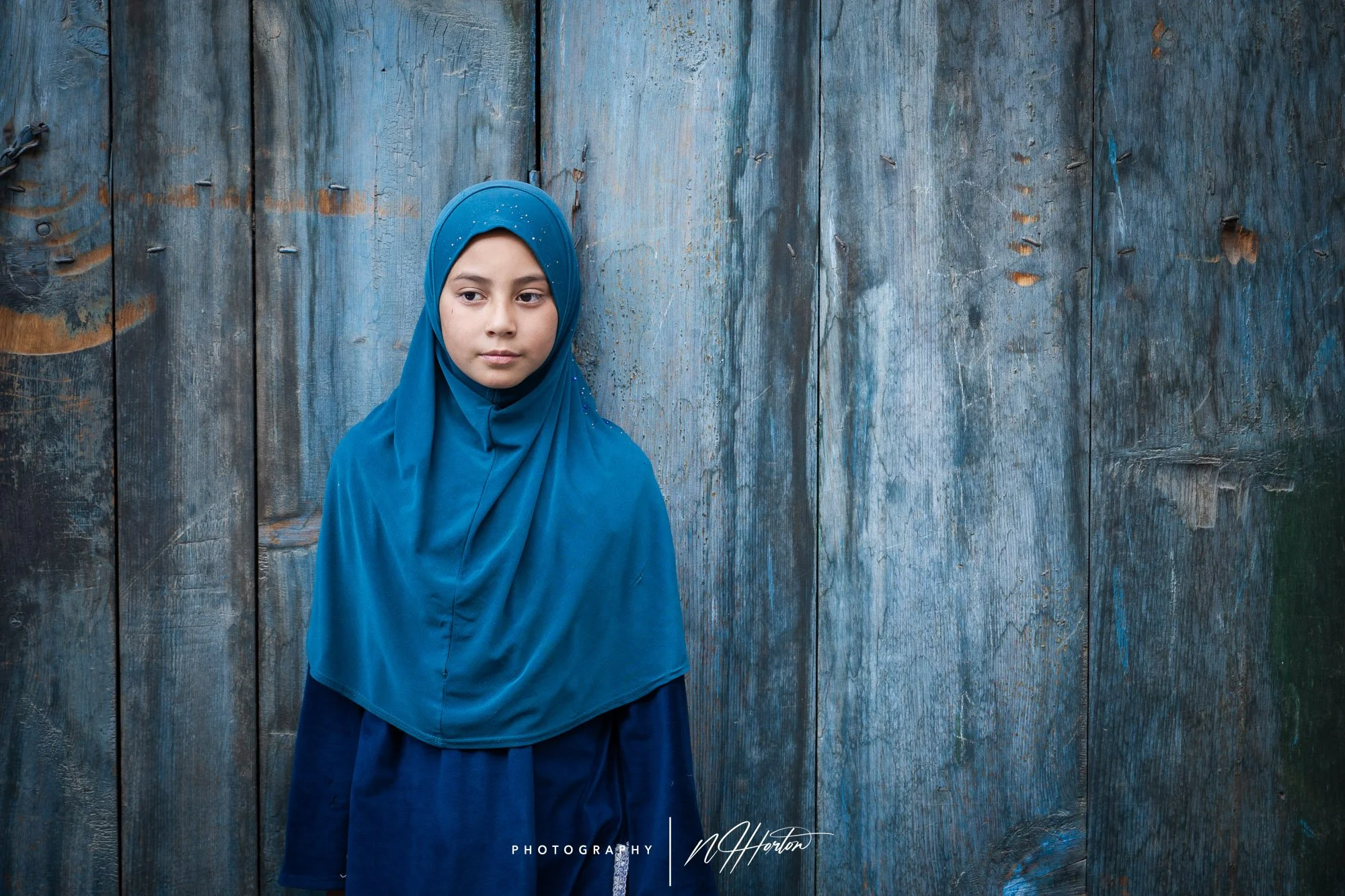 Young girl against a blue door, Kargil, Ladakh