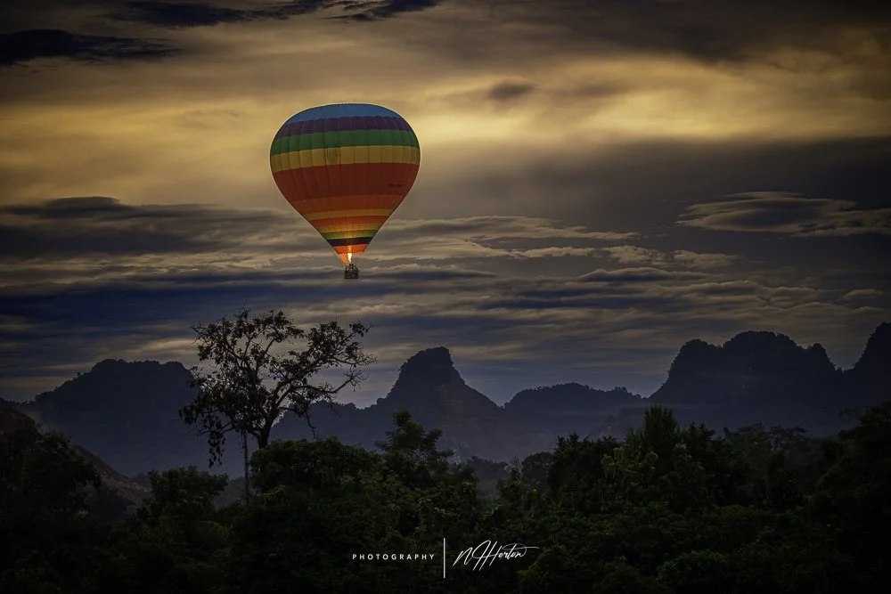 Hot air ballon over karst mountains at sunrise, Vang Vieng, Laos.