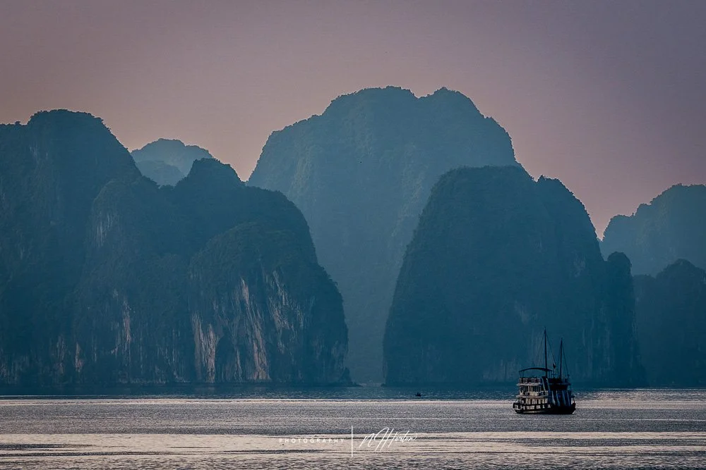 Sunset over boat and mountains in Halong Bay, North Vietnam.