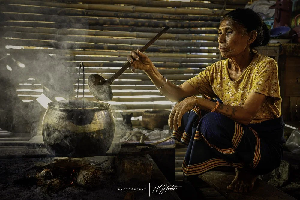 Tribal woman cooking in a traditional house, Sumba