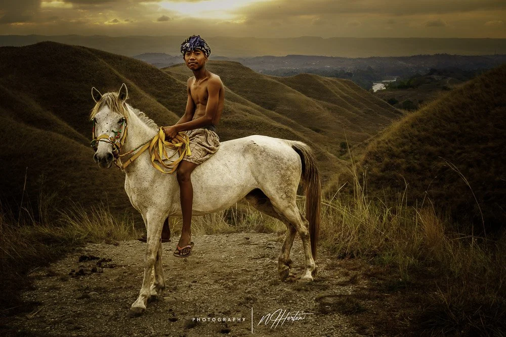 Boy on horse against rolling hills in Sumba