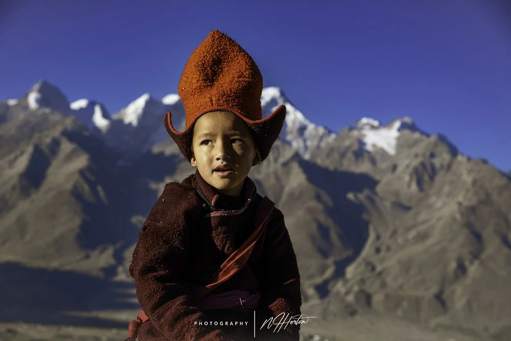 Young monk against snow peaked mountains in Zanskar valley