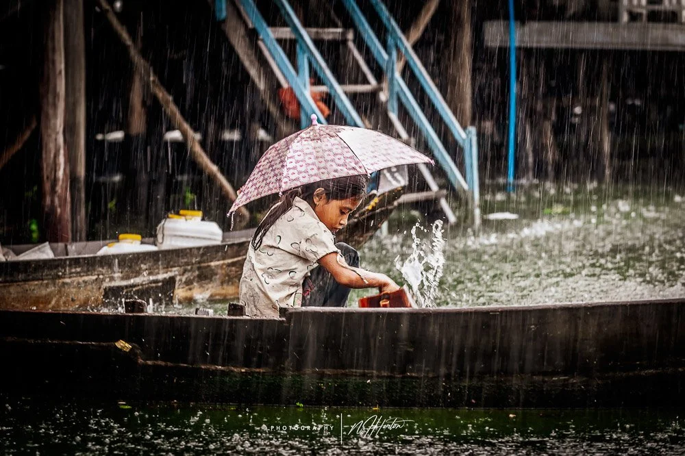 Girl caught in rain, Kompong Phluk, Cambodia.
