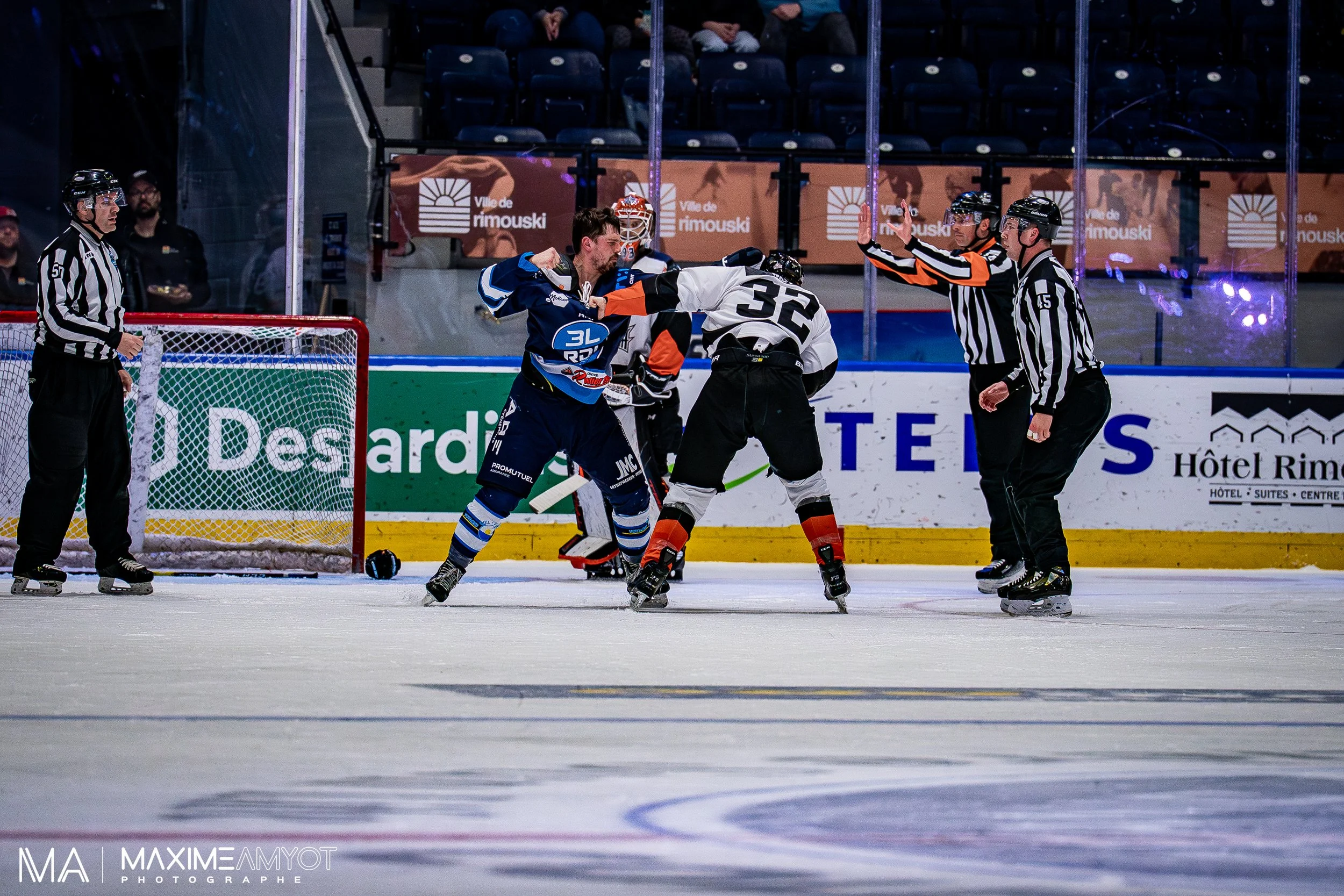 Une dispute entre deux joueurs de hockey sur glace sur la glace, avec deux arbitres interviennent pour séparer les joueurs.