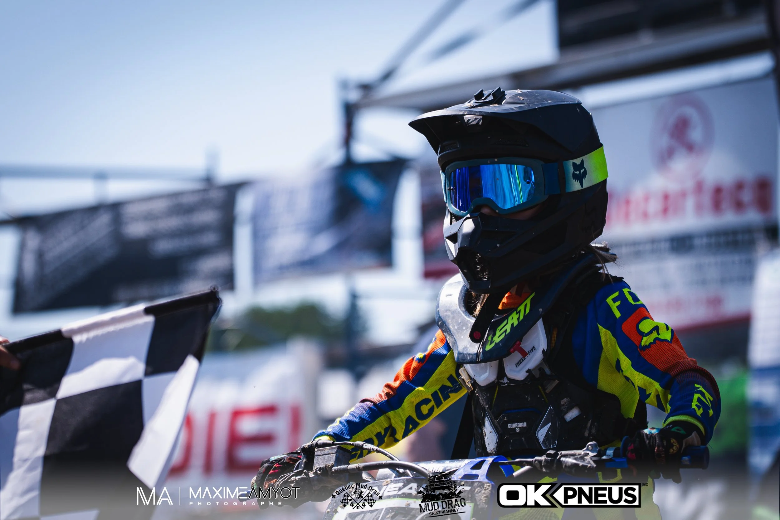 Motocross avec un pilote portant un casque noir et des lunettes de protection bleu, en train de participer à une course.