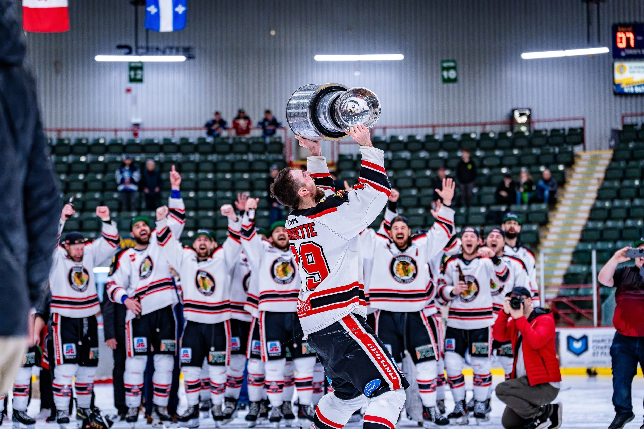 Une équipe de hockey célébrant la victoire avec un trophée sur la patinoire.
