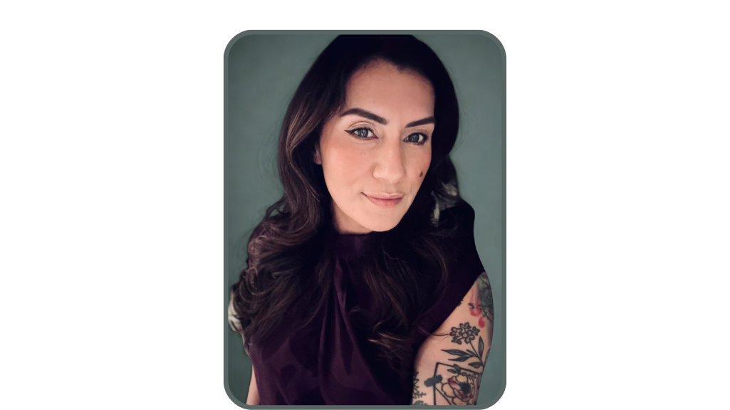 A woman with brown hair, smiling, crossed arms, wearing a white blouse, standing against a gray background.