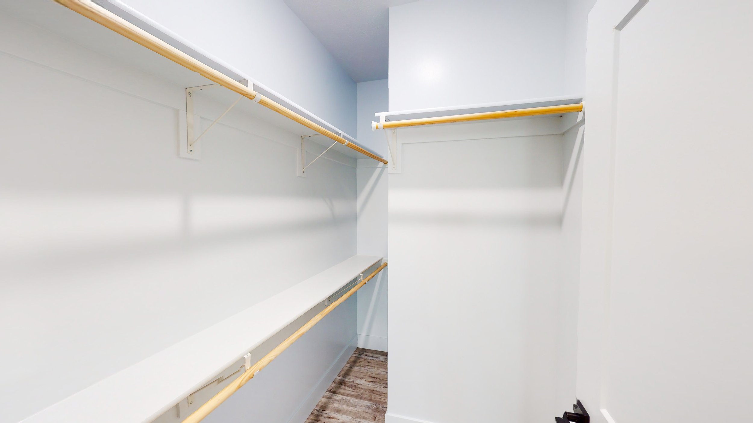 Empty walk-in closet with shelves and hanging rods