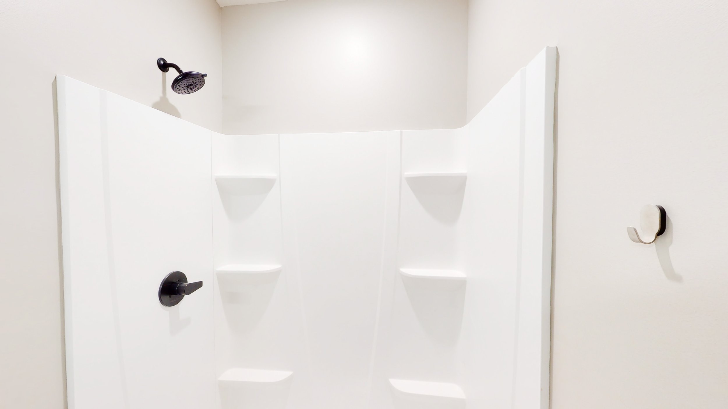 White shower stall with corner shelves and a black showerhead