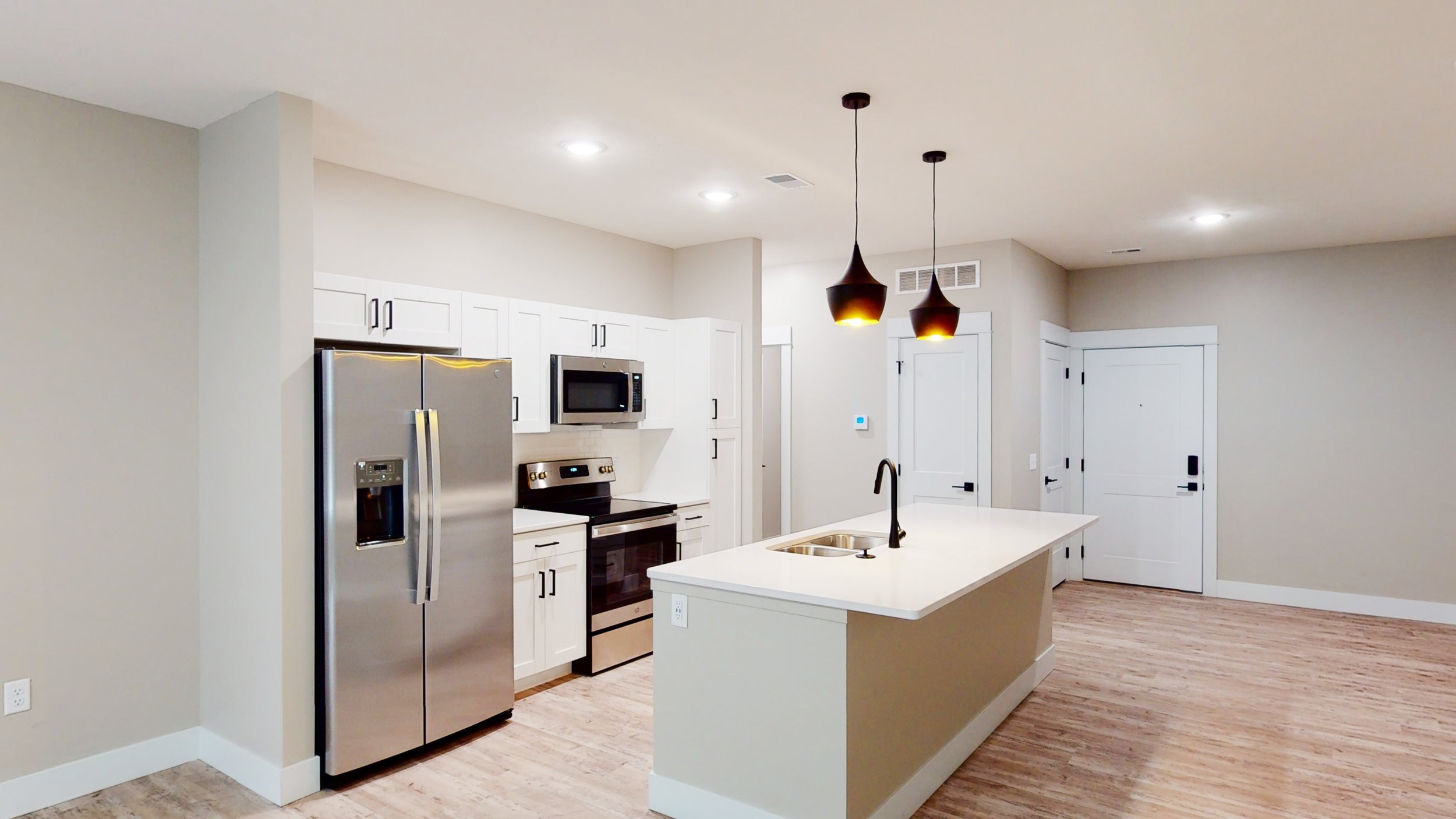 Modern kitchen with stainless steel appliances, white cabinets, and an island with pendant lighting.