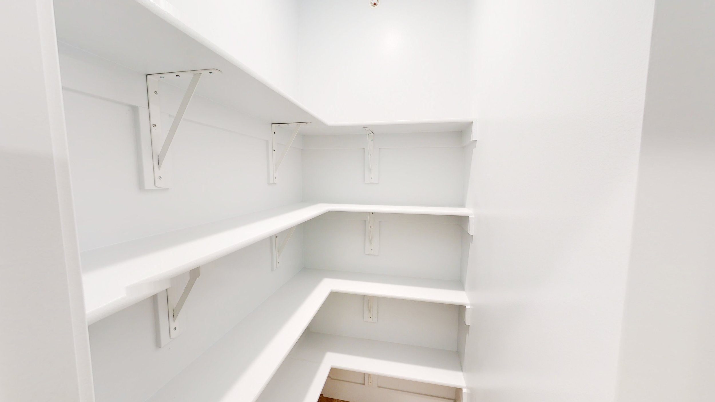 Empty white pantry with built-in shelves.