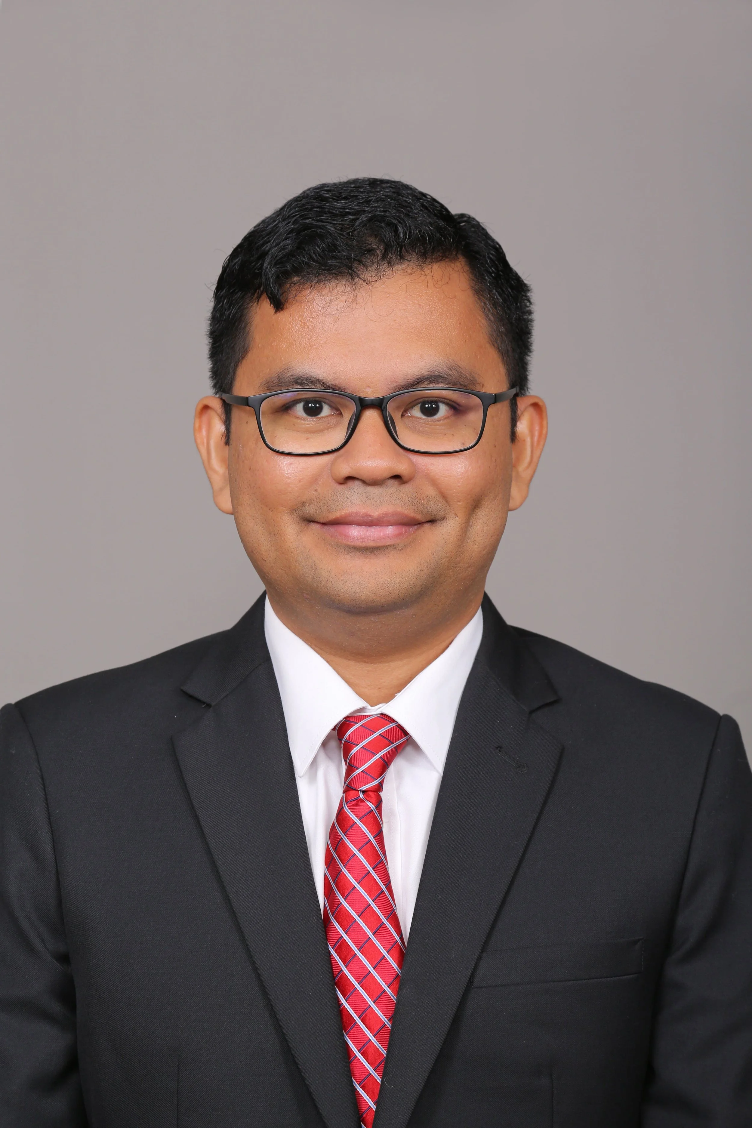 Professional portrait of a man in a suit with a name badge that reads 'RAFIZI', smiling at the camera.
