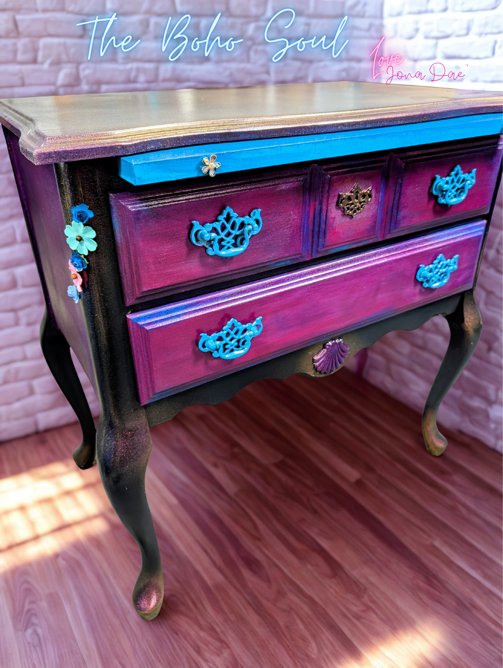 A whimsical boho-style dresser featuring a deep blue frame, vibrant pink drawer fronts, and custom floral hardware, perfect for adding a pop of color to any room.
