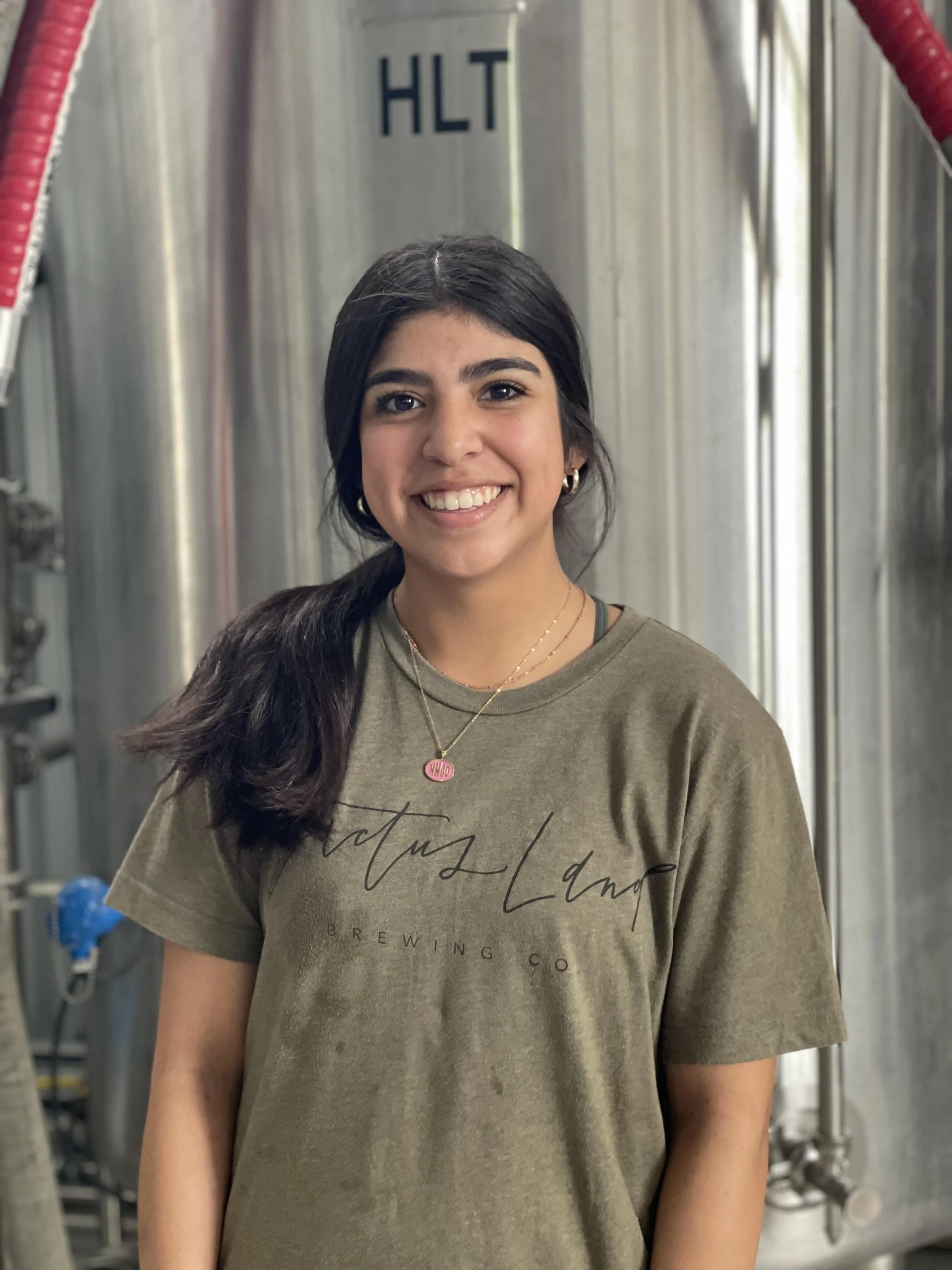 Woman smiling in front of brewery equipment